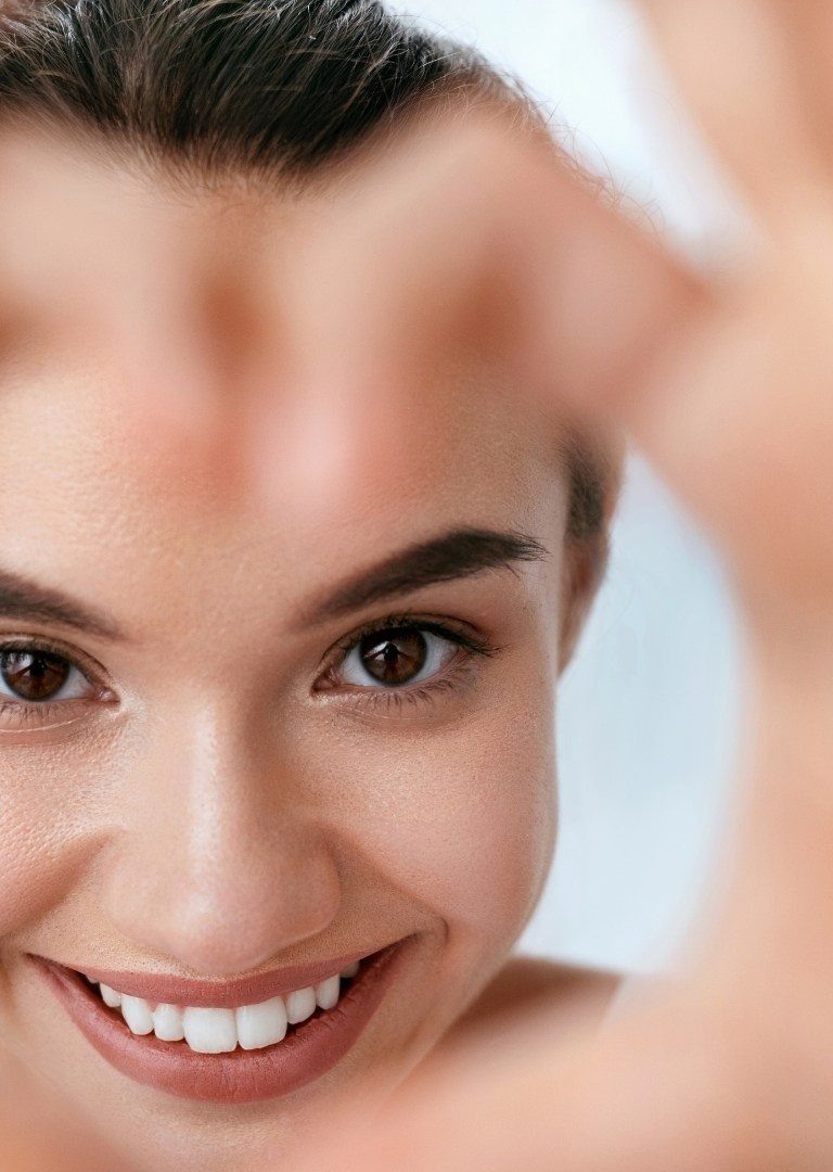 Smaidīga sieviete ar glītiem zobiem rāda sirsniņu